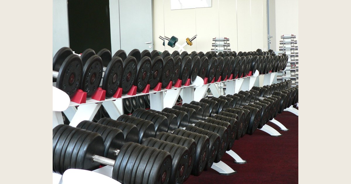 Rows of fixed-weight dumbbells on racks in a gym